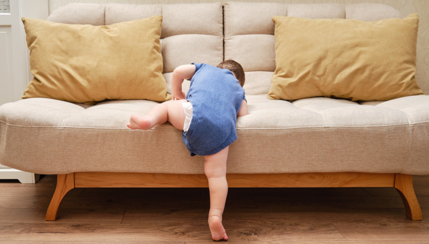 Ein Kleinkind klettert auf ein Sofa.